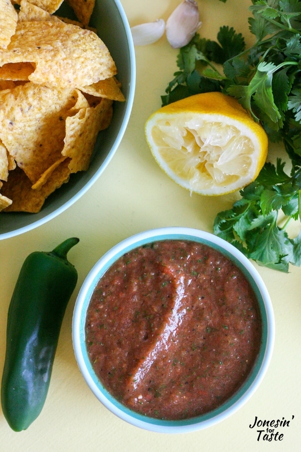 A bowl of salsa next to a lemon cilantro and jalapeno