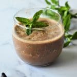 a cup of chocolate smoothie with a mint sprig in it