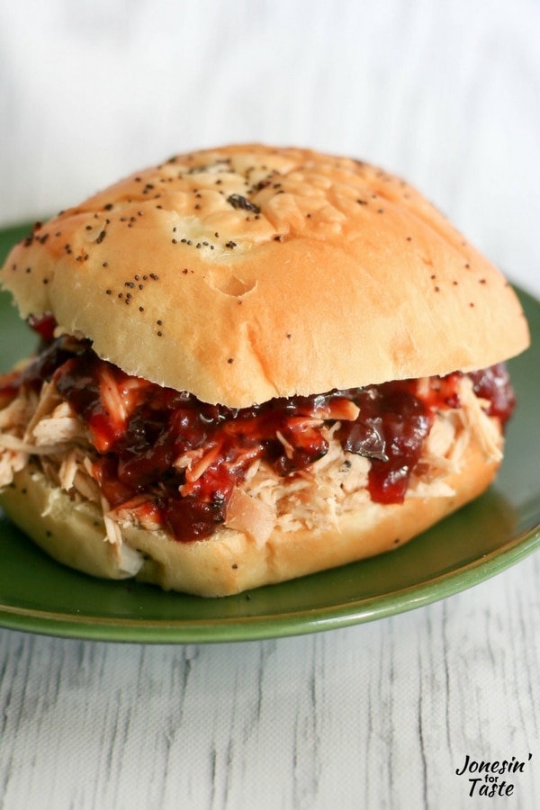 A onion bun with Slow Cooker Cranberry Chicken on a green plate