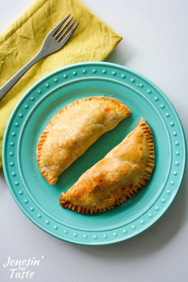 Baked empanadas on a blue plate next to a yellow napkin