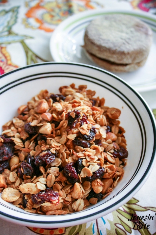 A bowl of granola next to a plate with an english muffin