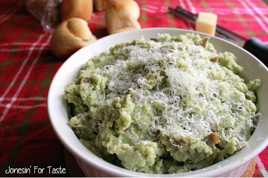 A casserole dish with pesto mashed potatoes in front of rolls
