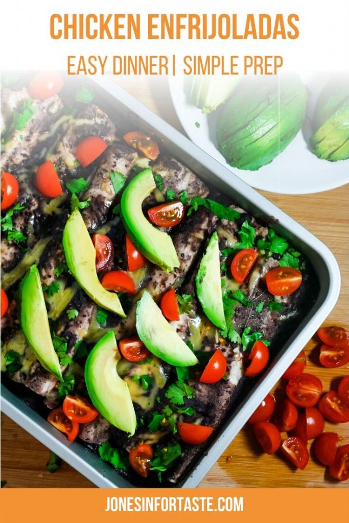 a pan of enfrijoladas topped with avocados, cilantro, and sliced tomatoes