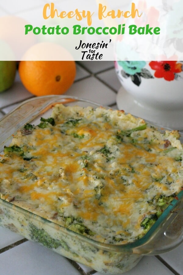 A glass casserole dish of Cheesy Ranch Potato Broccoli Bake in front of a white and floral pitcher on a grey tile countertop