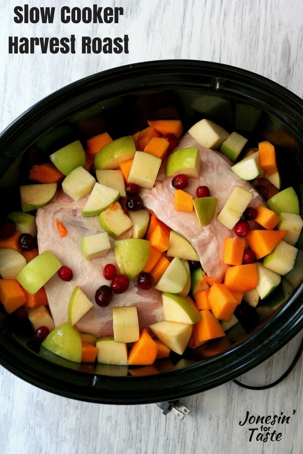 In a black slow cooker, uncooked butternut squash, apples, fresh cranberries, and a pork roast combine together for a perfect fall roast.