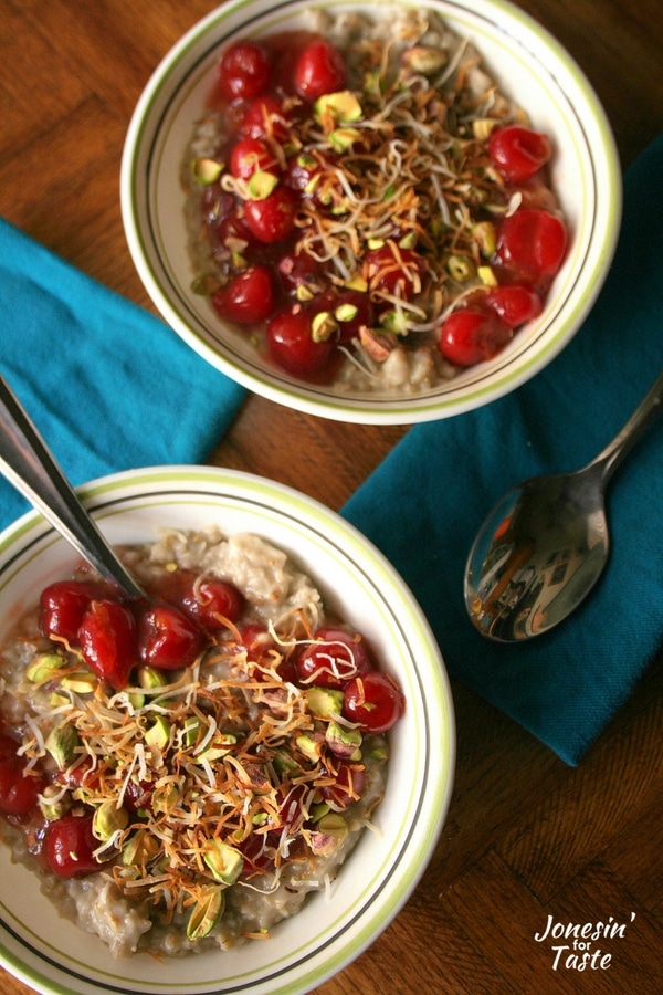 Looking down on two bowls of Slow Cooker Cherry Coconut Steel Cut Oatmeal with blue napkins on a wooden table.