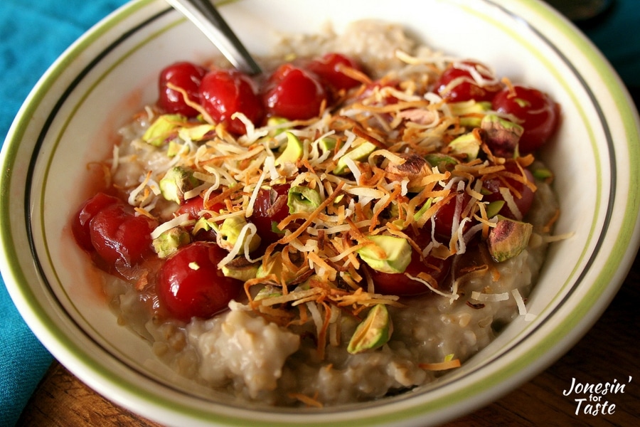 Just a bowl of Slow Cooker Cherry Coconut Steel Cut Oatmeal topped with cherry compote, shredded coconut, and chopped pistachios.