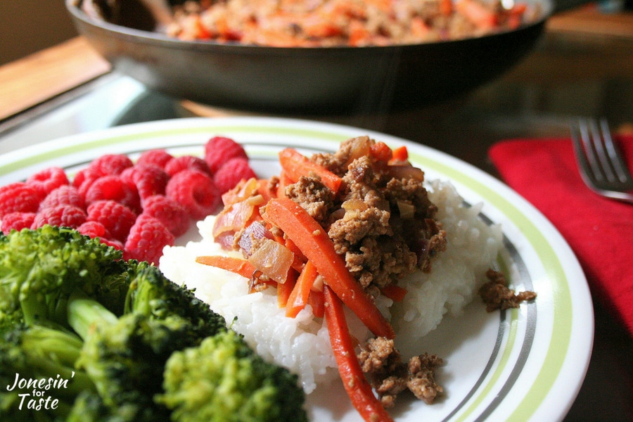 A scoop of hamburger and carrot skillet meal on top of rice.