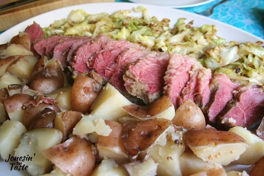 A platter with cabbage, Slow Cooker Corned Beef and potatoes in rows.