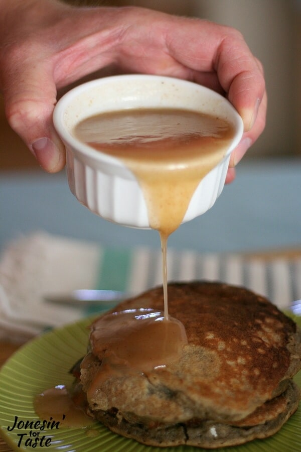 Apple syrup being poured over a stack of pancakes.