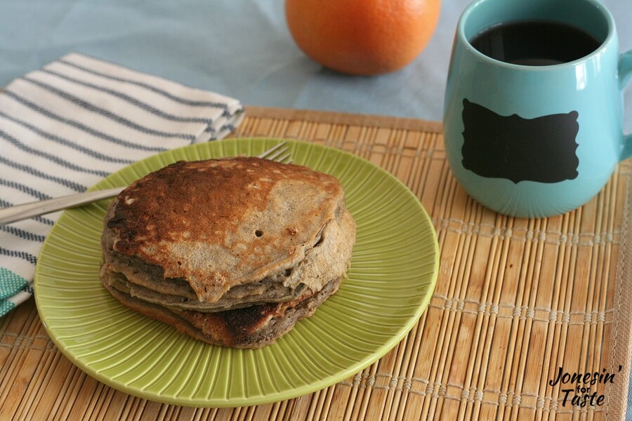 A plate of sourdough pancakes on a bamboo placemat and a blue mug on a light blue tablecloth