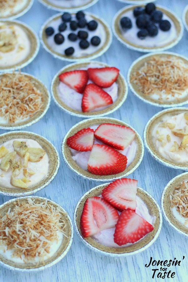 A row of Mini No Bake Strawberry Cheesecakes in between rows of coconut and banana cheesecakes.