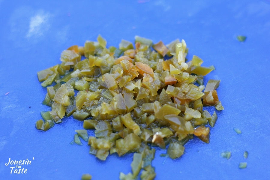 Finely chopped jalapeno peppers on a blue cutting board