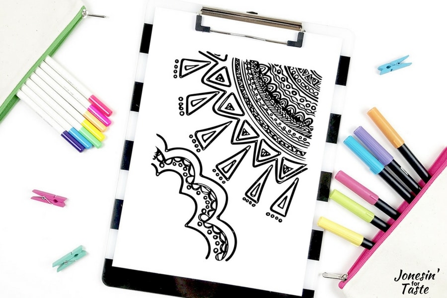A sun coloring page on a clipboard surrounded by coloring supplies