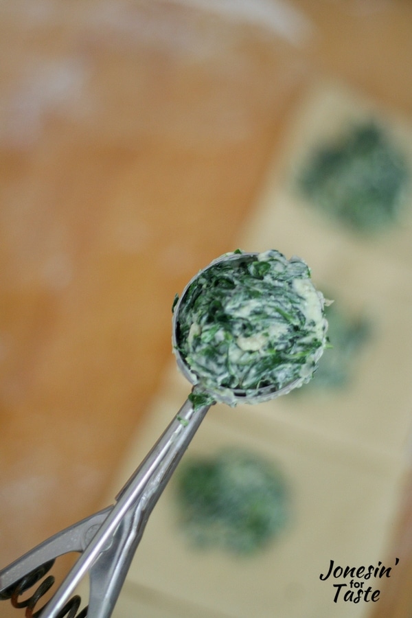 A mini cookie scoop full of spinach filling for Easy Mini Spinach Calzones.