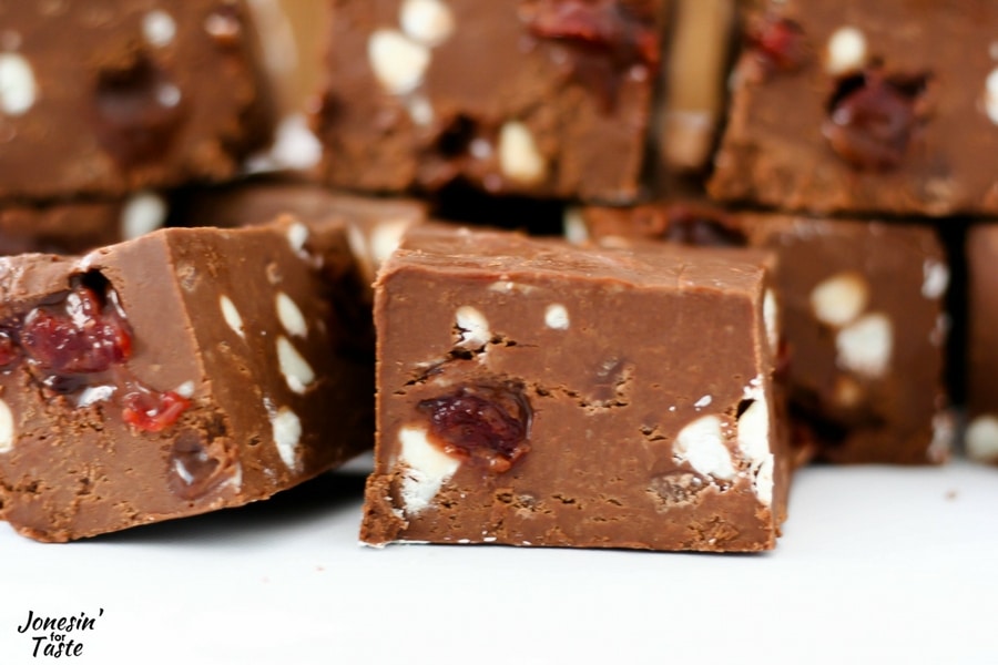 A large square of fudge with bits of white chocolate chips and chunks of cherries.