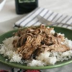 Slow Cooker Garlic Balsamic Pork drizzled with extra balsamic vinegar on top of white rice on a green plate.