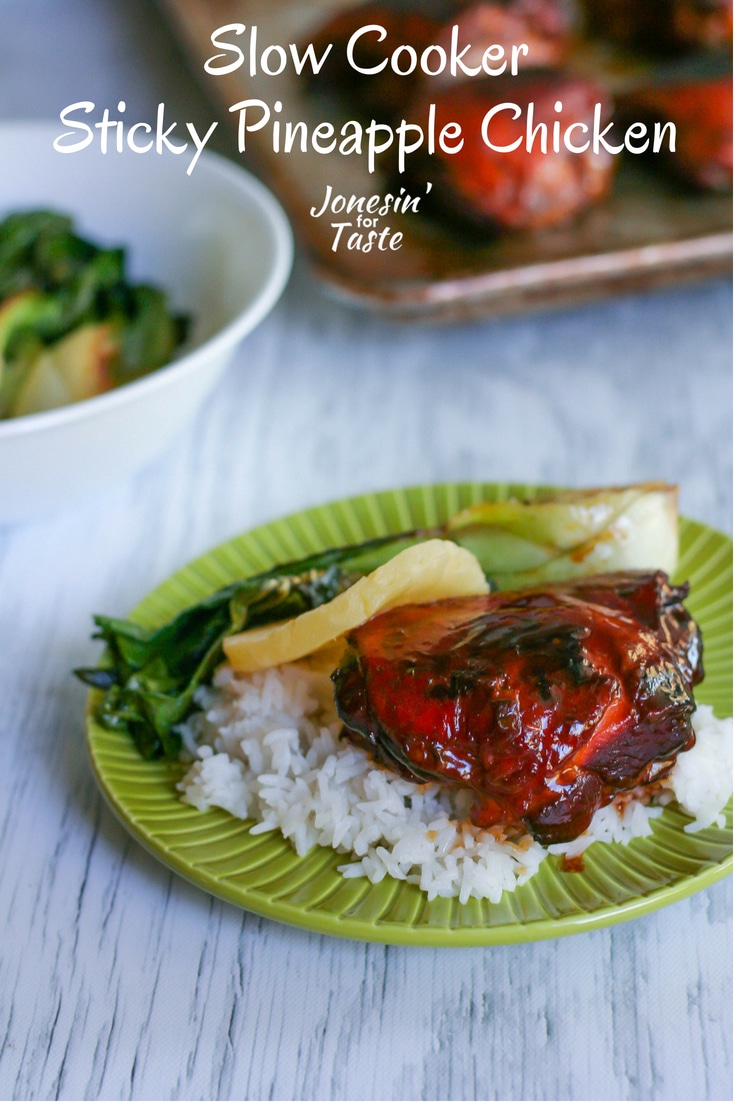 A white wooden table top with a green plate filled with rice, slow cooker sticky pineapple chicken, and baby bok choy with a bowl of baby bok choy and a tray of chicken in the background.