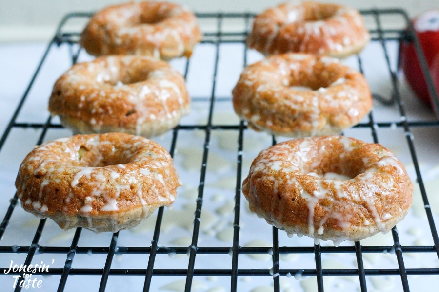 6 Baked Cinnamon Apple Doughnuts iced and drying on a cooling rack
