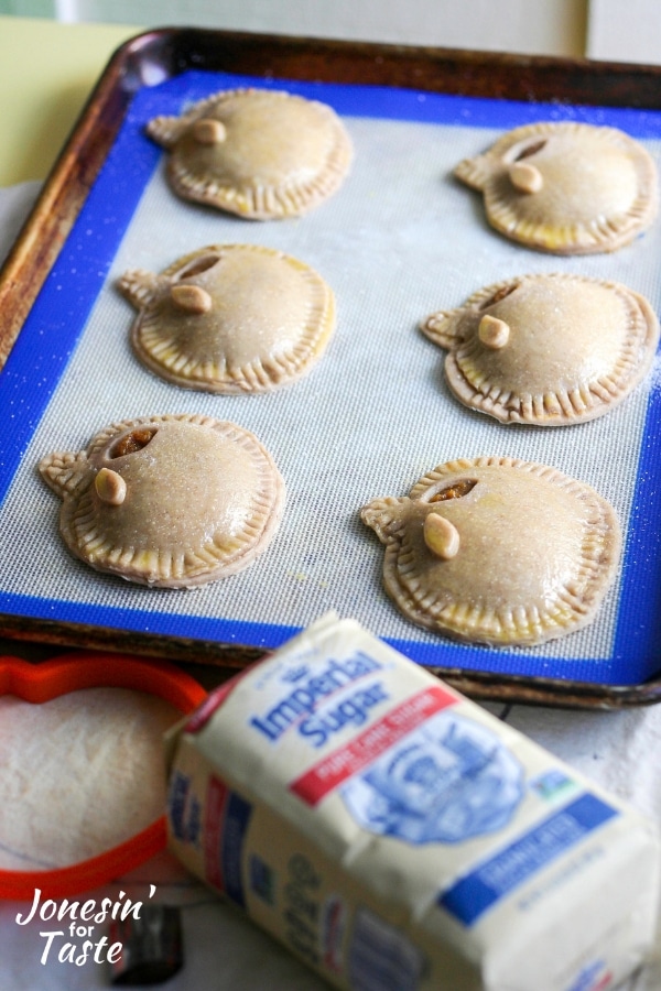 Unbaked pumpkin pasties on a cookie sheet.