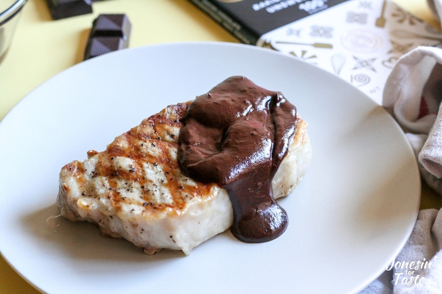A pork chop on a plate with chipotle chocolate sauce