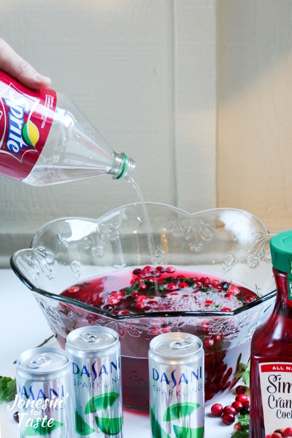 Sprite being poured into a punch bowl of festive cranberry holiday punch