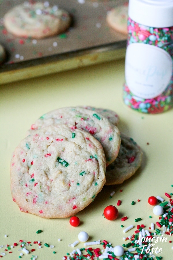 Baked Christmas Sprinkle Pudding cookies next to a pile of sprinkles