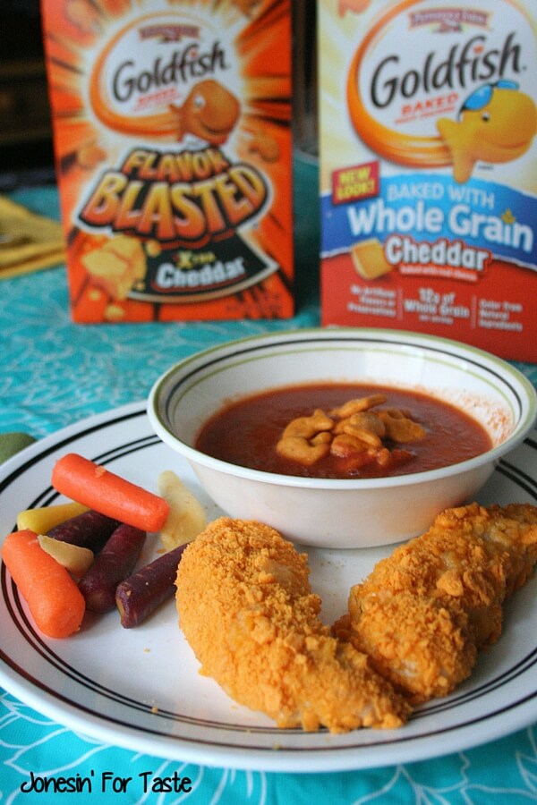 A plate of Goldfish cracker crusted chicken with boxes of Goldfish in the background