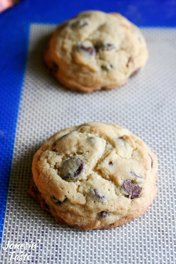 Two baked chocolate chip cookies on a cookie sheet