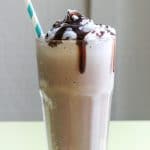 A glass full of frozen hot chocolate topped with whipped cream and chocolate syrup,