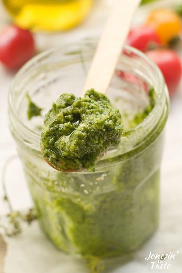 a jar of pesto with a spoon full of the sauce resting on the top of the open jar