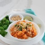 A white bowl of sweet potato curry set in a white plate with curry toppings