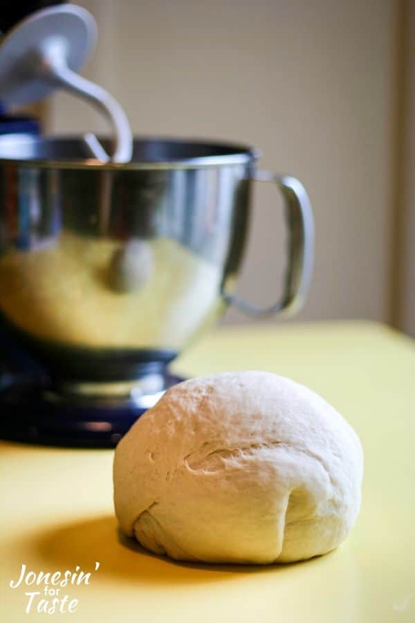 a ball of pizza dough on a table in front of a mixer