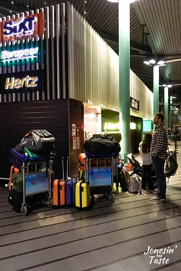 luggage trolleys loaded with baggage outside a car rental counter