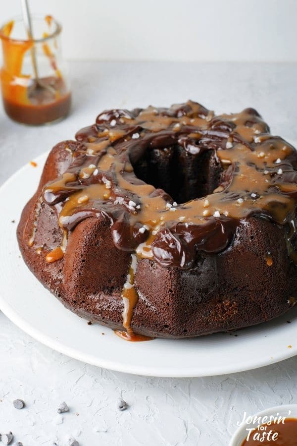 a chocolate bundt cake topped with chocolate and caramel sauces on a white plate