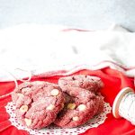 red velvet cookies on a doily on top of red fabric