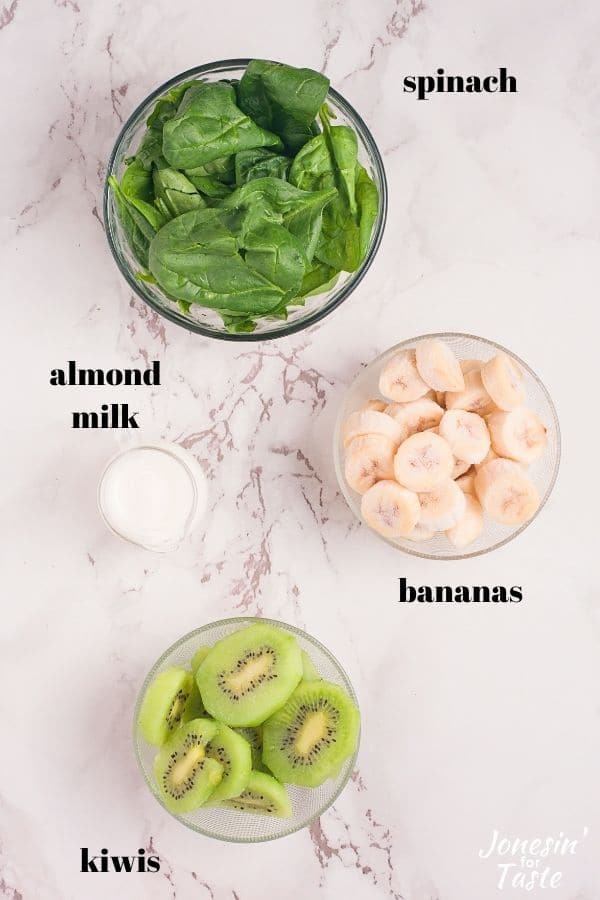 bowls of spinach, chopped bananas, halved kiwis, and almond milk