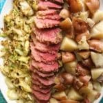 columns of cooked shredded cabbage, sliced corned beef, and quartered potatoes sit on a white platter