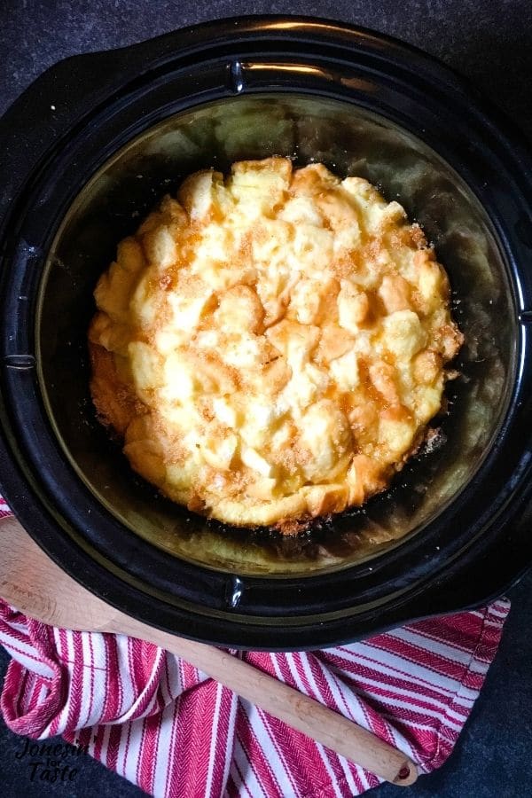a slow cooker with bread pudding and crystallized bits of brown sugar in the crevices of bread cubes