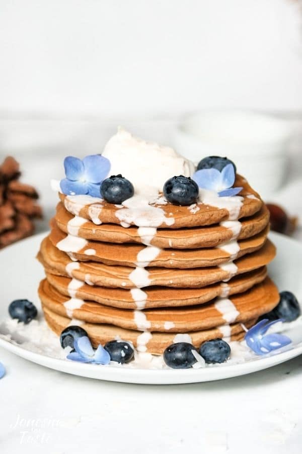 a stack of gingerbread pancakes with syrup drizzling down the sides
