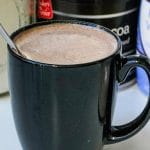 a black mug with hot cocoa and a spoon