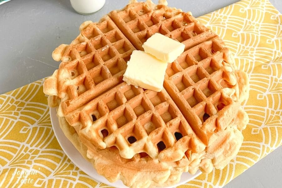 2 waffles on a plate on a table with a yellow runner