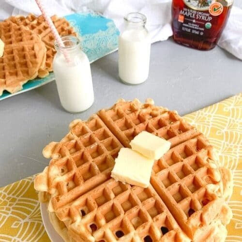 waffles topped with pads of butter on a breakfast table