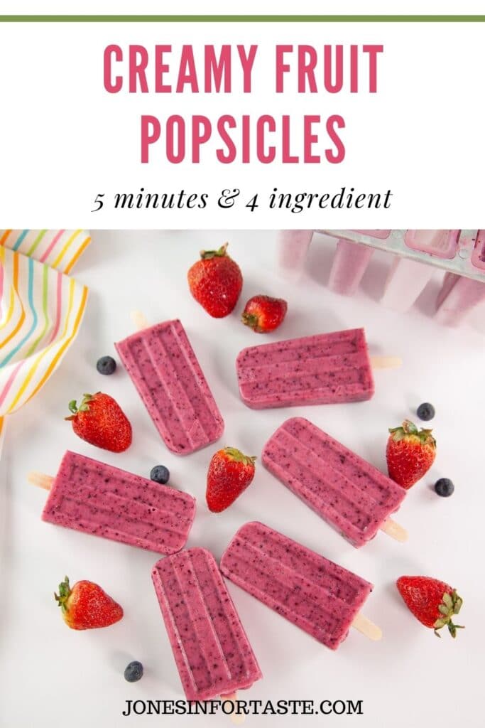 pink fruit popsicles on a white background with strawberries and blueberries around them