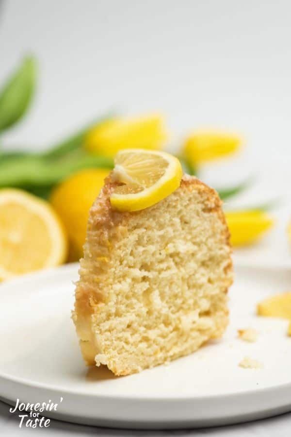 a slice of cake standing up on a white plate with a slice of lemon on top