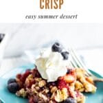 a blue plate with a scoop of peach blueberry crisp and whipped cream with a text graphic above it with the name of the recipe